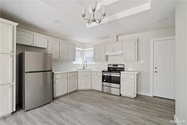 a kitchen with a refrigerator a stove a sink and white cabinets