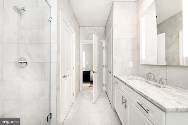 a bathroom with a granite countertop sink two mirror and a shower