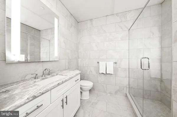 a bathroom with a granite countertop sink a toilet and shower