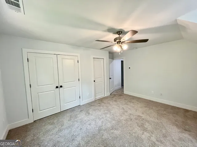 an empty room with chandelier fan and windows
