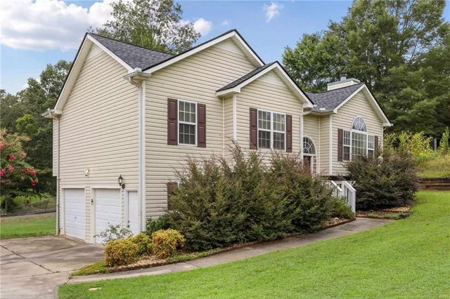 a view of a white house next to a yard and large trees