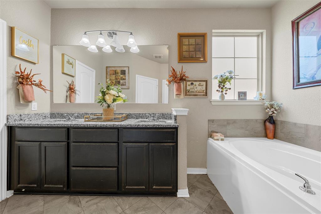 10620 Langham Drive Waco, TX 76708 - Photo 11 of 30 a bathroom with a granite countertop sink a mirror a vanity and a bathtub