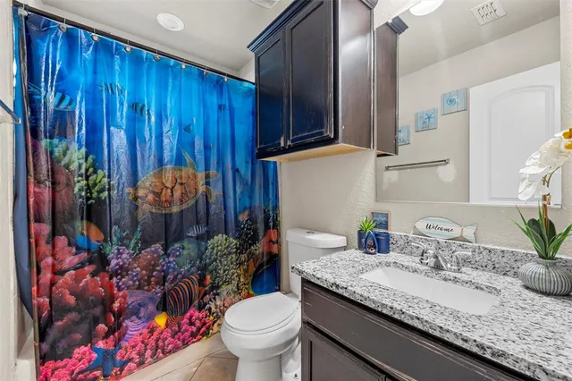 a bathroom with a granite countertop sink and a toilet