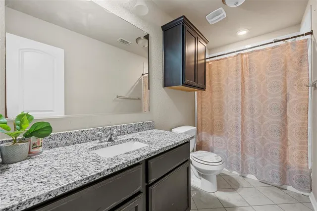 a bathroom with a granite countertop sink a toilet and mirror