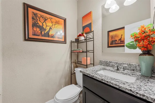 a bathroom with a granite countertop sink and a painting on the wall