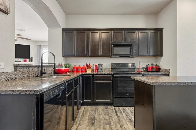 a kitchen with granite countertop a sink stainless steel appliances and cabinets