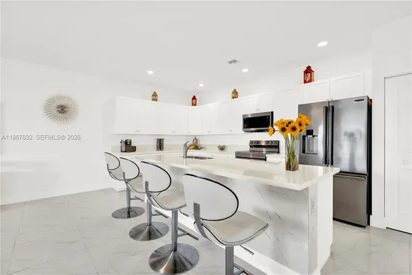 a white kitchen with a sink stainless steel appliances and cabinets