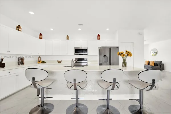 a kitchen with stainless steel appliances granite countertop a sink and white cabinets with wooden floor