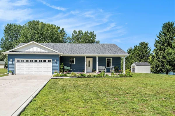 a front view of a house with garden and trees