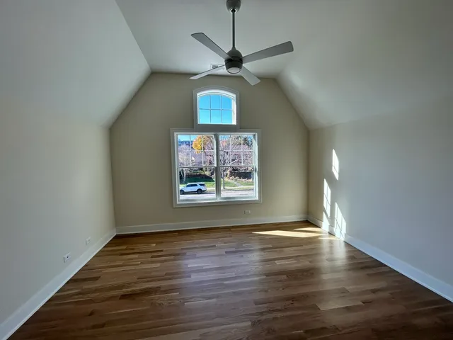 a view of a room with wooden floor a ceiling fan and a window