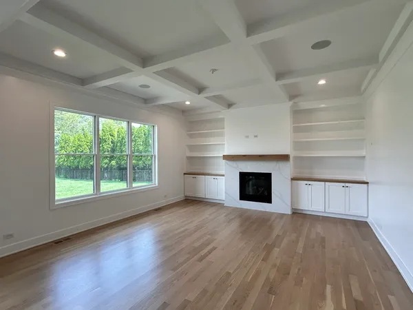 an empty room with wooden floor fireplace and windows