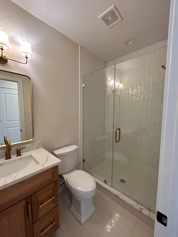 a bathroom with a shower sink vanity mirror and toilet