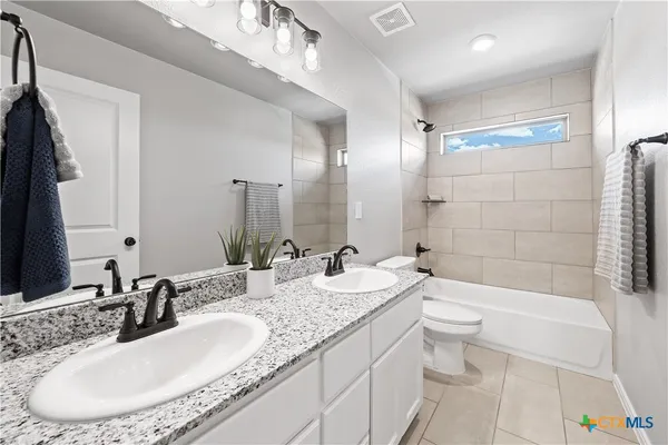 a bathroom with a granite countertop sink a toilet a mirror a bathtub and shower