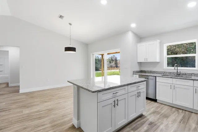 a kitchen with white cabinets and window