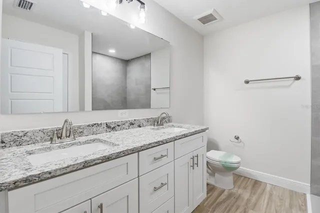 a bathroom with a granite countertop sink a toilet and a mirror