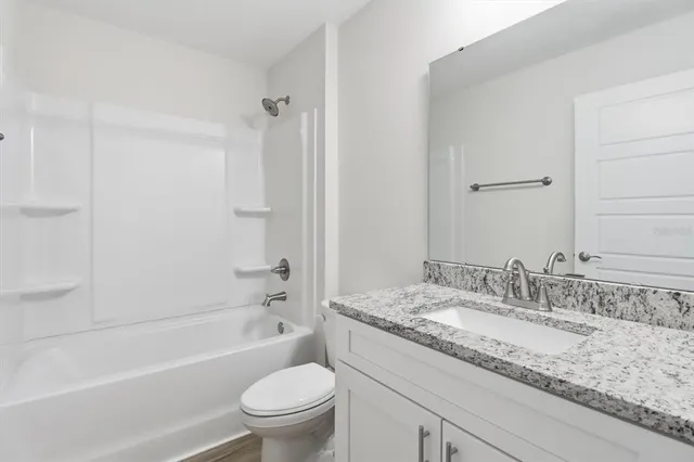 a bathroom with a granite countertop sink a toilet and shower