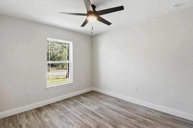an empty room with a window and a ceiling fan