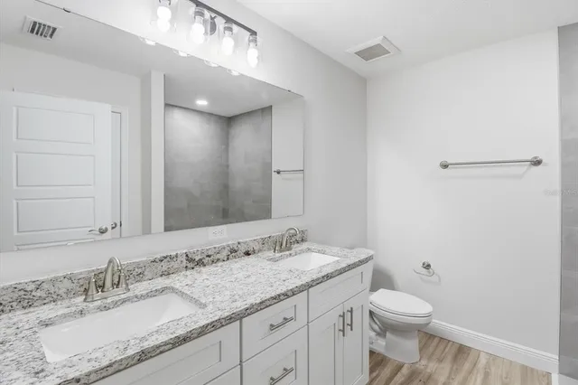 a bathroom with a granite countertop sink a toilet and a mirror
