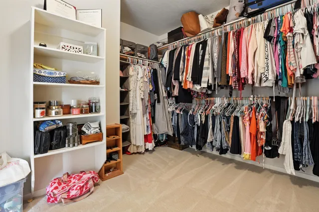 a view of walk in closet with clothes and shoes