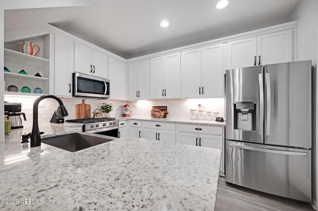a kitchen with granite countertop white cabinets and white appliances