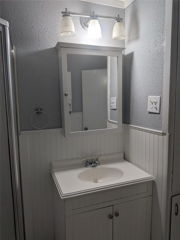 2009 County Road 4619 Athens, TX 75752 - Photo 28 of 36 Bathroom with a textured wall, vanity, and wainscoting