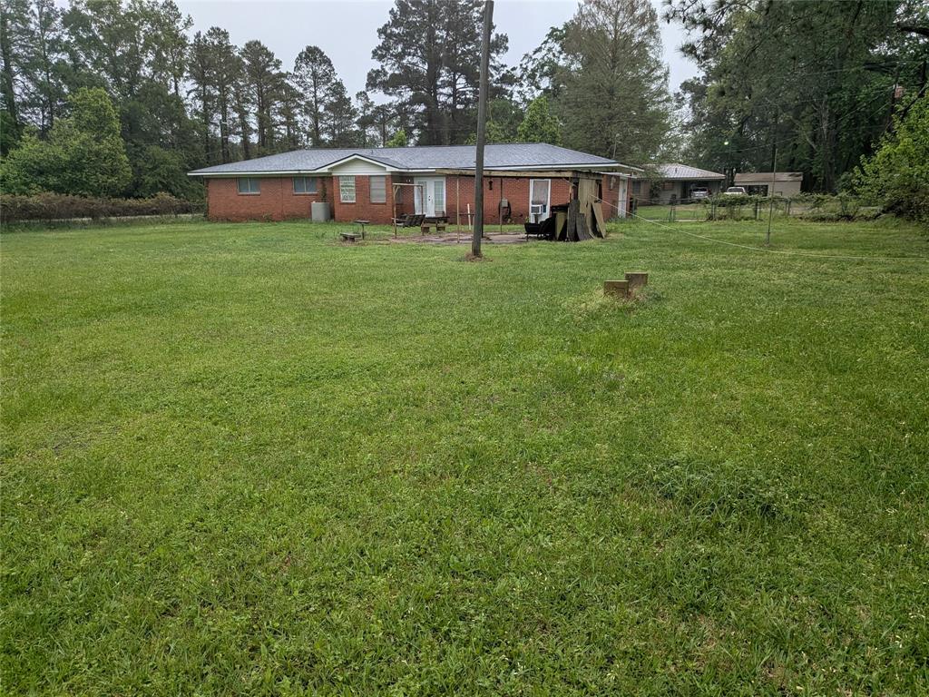 2009 County Road 4619 Athens, TX 75752 - Photo 6 of 36 Rear view of property featuring a lawn, view of wooded area, and brick siding