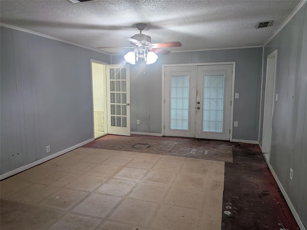 2009 County Road 4619 Athens, TX 75752 - Photo 10 of 36 Empty room with french doors, crown molding, a ceiling fan, a textured ceiling, and wooden walls
