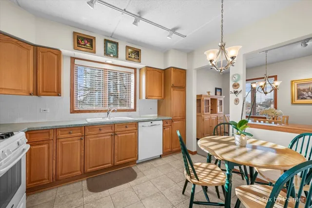 a open kitchen with stainless steel appliances granite countertop a dining table chairs and a refrigerator