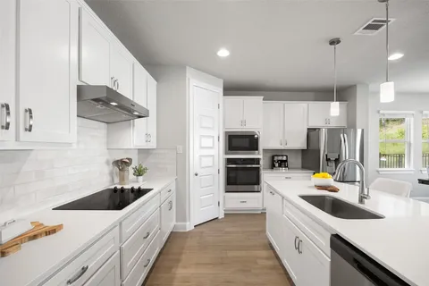 a kitchen with stainless steel appliances a sink stove refrigerator and cabinets