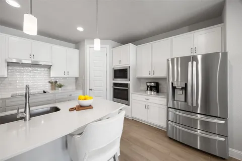a kitchen with stainless steel appliances a refrigerator sink and white cabinets