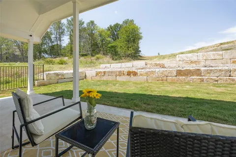 a view of a chairs and table in patio next to a yard