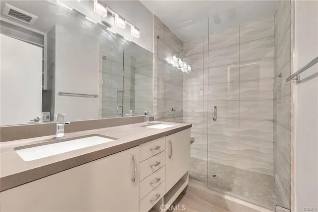 a bathroom with a double vanity sink mirror and shower