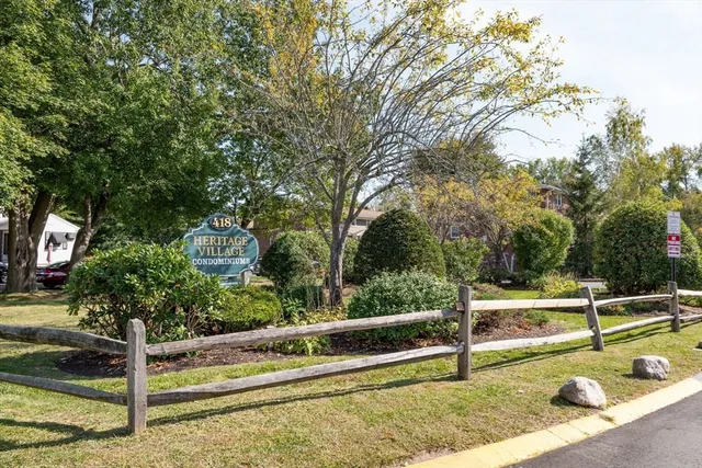 a view of a house with a small yard and large trees