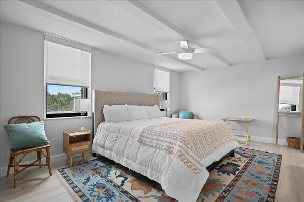 a bedroom with a bed wooden floor and a lamp on dresser
