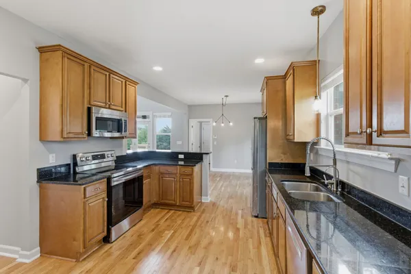 a kitchen with stainless steel appliances granite countertop a sink a stove and a refrigerator