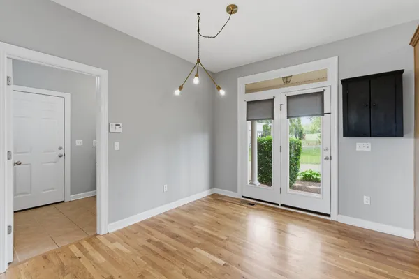 a view of kitchen and empty room with wooden floor