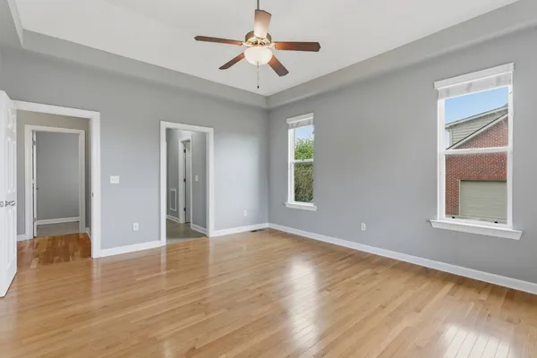 an empty room with wooden floor and ceiling fan