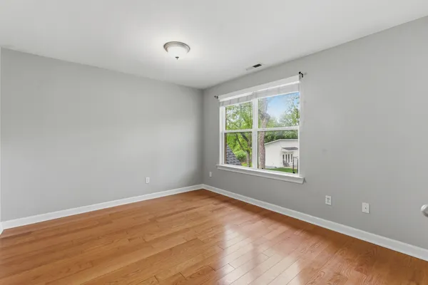 a view of an empty room with wooden floor and closet