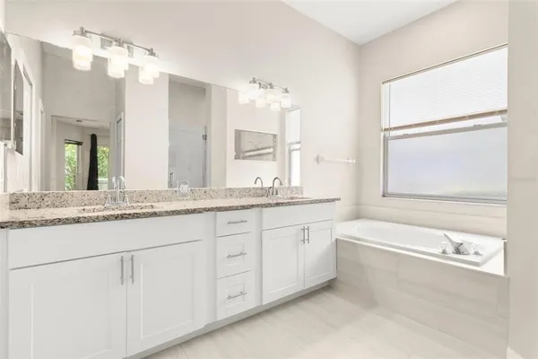 a bathroom with a granite countertop sink mirror and a bathtub
