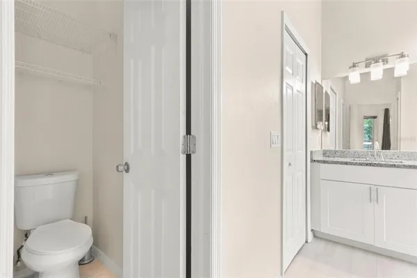 a bathroom with a granite countertop toilet a sink and a mirror