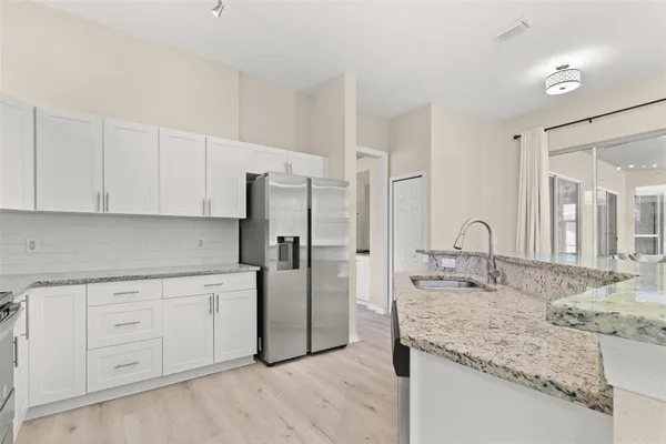 a kitchen with granite countertop a sink and refrigerator