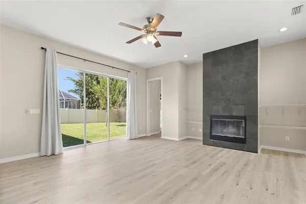 an empty room with wooden floor fan and windows