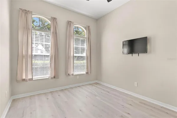an empty room with wooden floor and windows