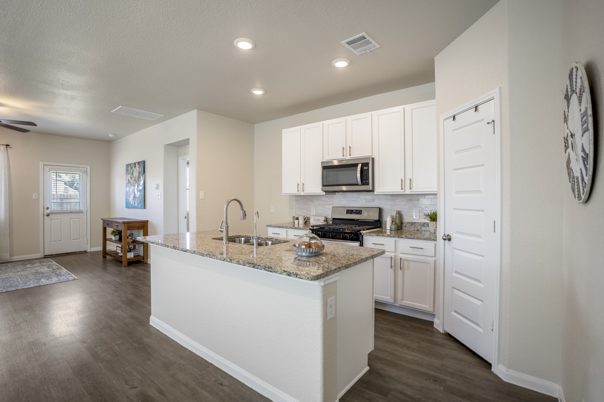 2355 Mount Locke Path Conroe, TX 77301 - Photo 10 of 47 From this angle, the kitchen feels even more connected to the rest of the first floor, with the island stretching toward the dining and living spaces on the left. The pantry sits just beyond the kitchen on the right, while the updated backsplash, cabinet hardware, granite counters, and stainless appliances keep the workspace feeling polished and practical.