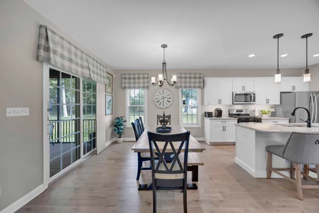 a kitchen with stainless steel appliances kitchen island granite countertop a dining table chairs and white cabinets