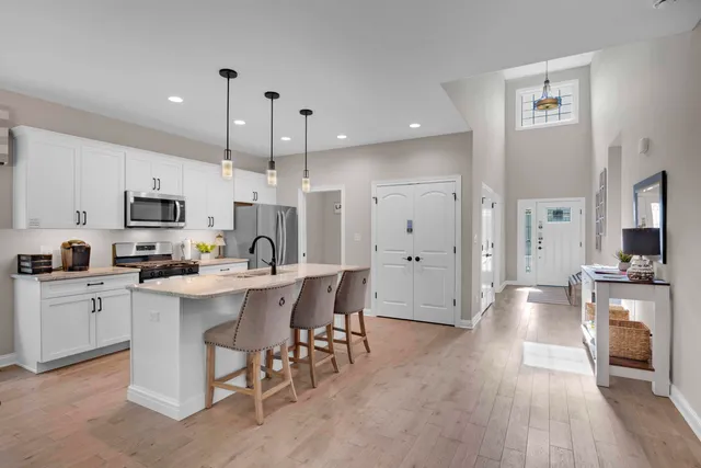 a kitchen with stainless steel appliances a sink a stove a refrigerator a center island and cabinets