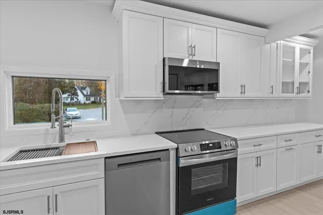 a kitchen with white cabinets and a stove with wooden floor