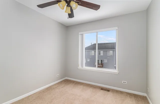 an empty room with a window and a ceiling fan