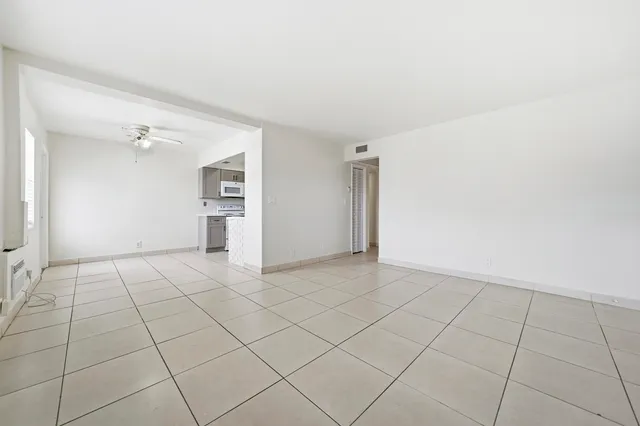 a view of an empty room and chandelier fan