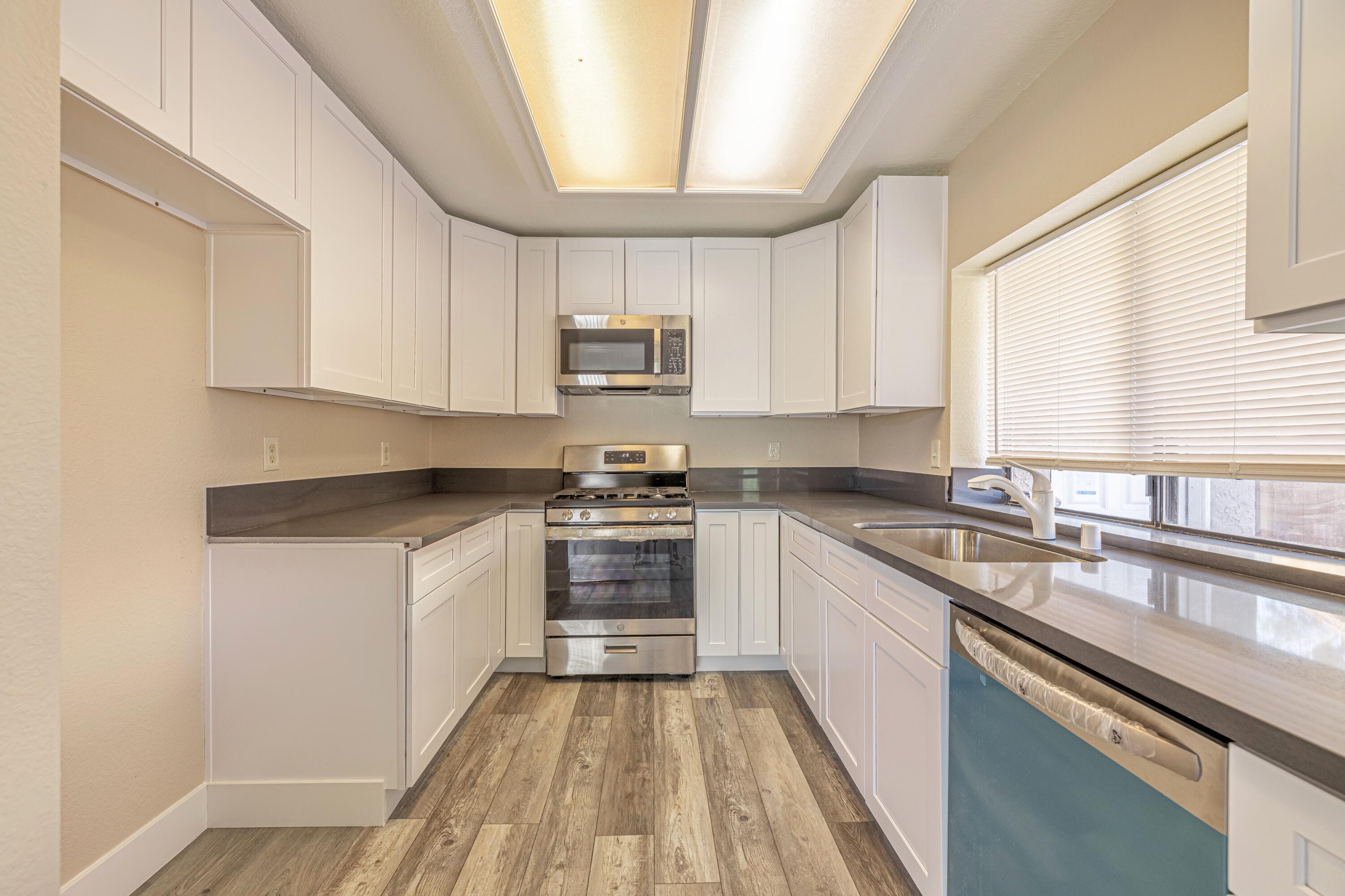 533 East Jackman Street Lancaster, CA 93535 - Photo 11 of 31 a kitchen with kitchen island white cabinets appliances a sink and a window